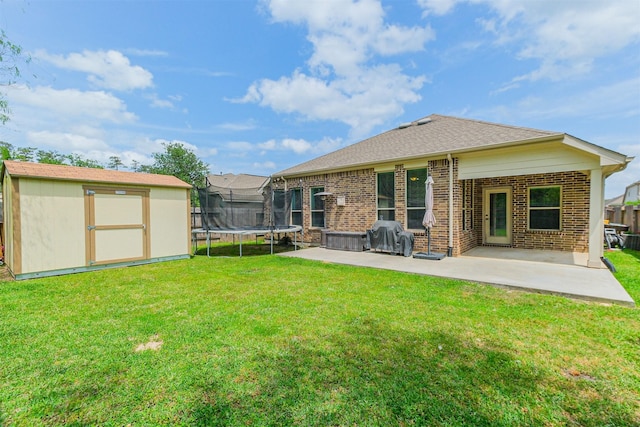 rear view of property with brick siding, a trampoline, an outdoor structure, a shed, and a patio