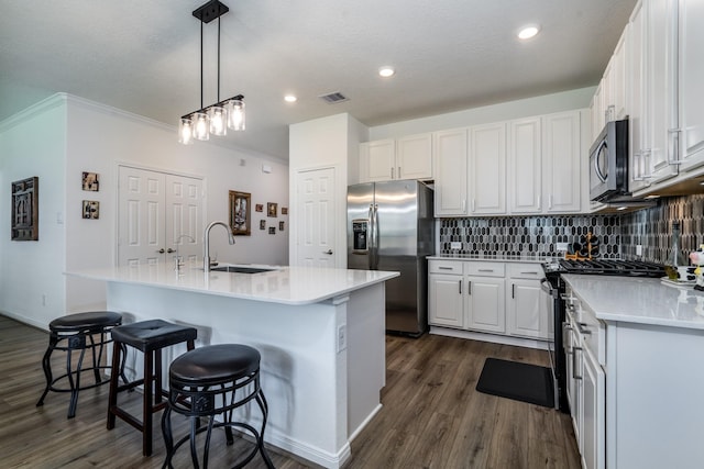 7702 Royal Oasis Ln, Cypress, TX 77433 - kitchen with white cabinets, stainless steel appliances, a sink, dark wood finished floors, and an island with sink