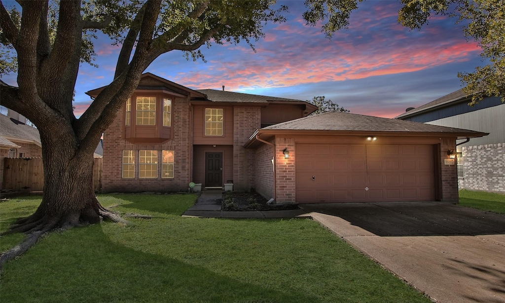 traditional-style home featuring an attached garage, brick siding, fence, and driveway