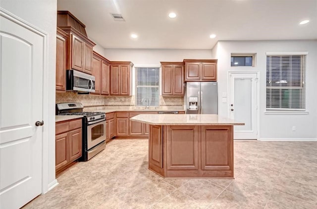 kitchen with backsplash, appliances with stainless steel finishes, a sink, and a kitchen island