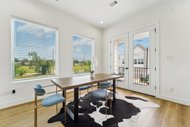 dining space with baseboards, light wood finished floors, visible vents, and plenty of natural light