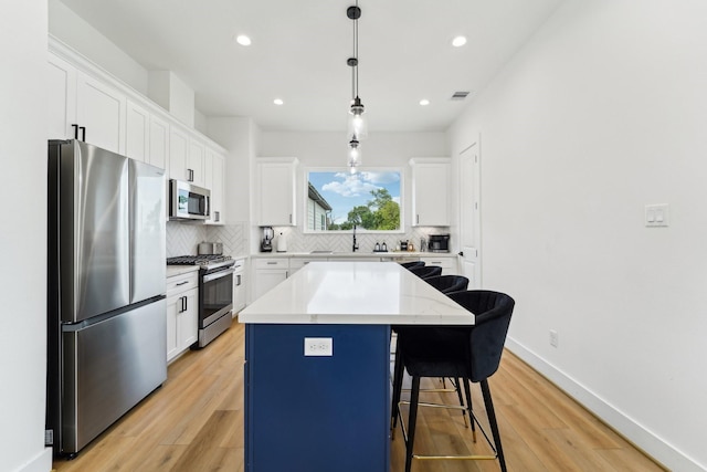 kitchen featuring stainless steel appliances, backsplash, visible vents, a kitchen island, and white cabinetry