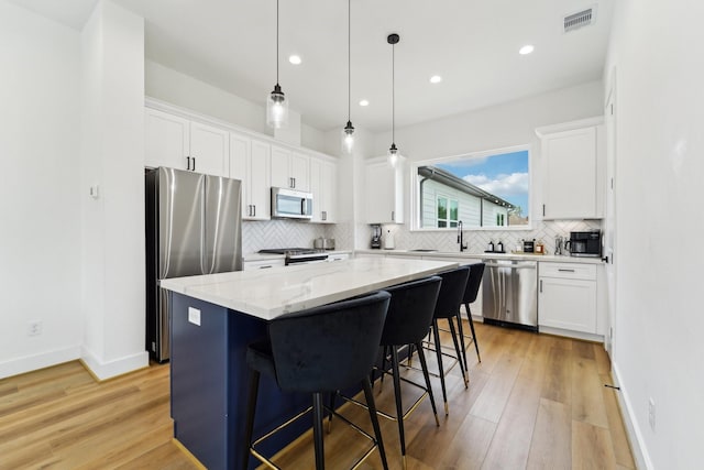 kitchen featuring white cabinets, a center island, visible vents, and appliances with stainless steel finishes