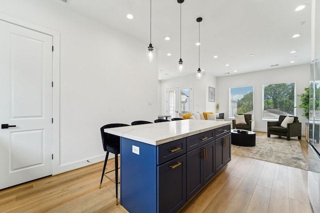 kitchen featuring a kitchen breakfast bar, hanging light fixtures, open floor plan, light wood-style floors, and recessed lighting