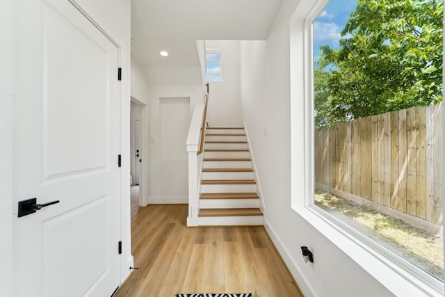 stairway with baseboards, wood finished floors, and recessed lighting