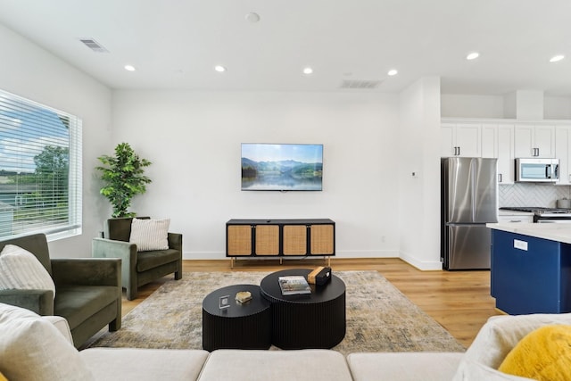living area featuring recessed lighting, visible vents, light wood finished floors, and baseboards