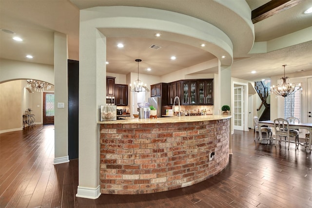 12603 Mostyn Ct, Magnolia, TX 77354 - bar featuring stainless steel appliances, dark wood-style flooring, arched walkways, and a notable chandelier