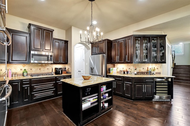 12603 Mostyn Ct, Magnolia, TX 77354 - kitchen with dark wood finished floors, beverage cooler, appliances with stainless steel finishes, and arched walkways