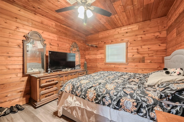 bedroom with wooden walls, light wood finished floors, wooden ceiling, and ceiling fan