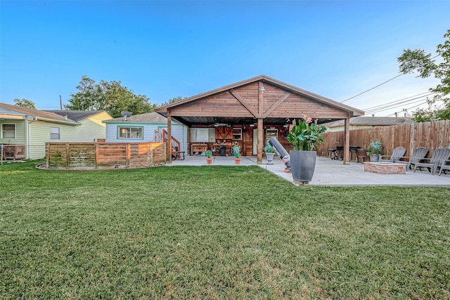 back of house with fence, a lawn, an outdoor fire pit, and a patio