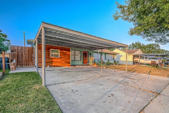 back of property featuring fence, a lawn, and driveway