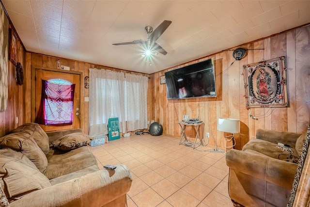 living room with ceiling fan, wooden walls, and light tile patterned floors