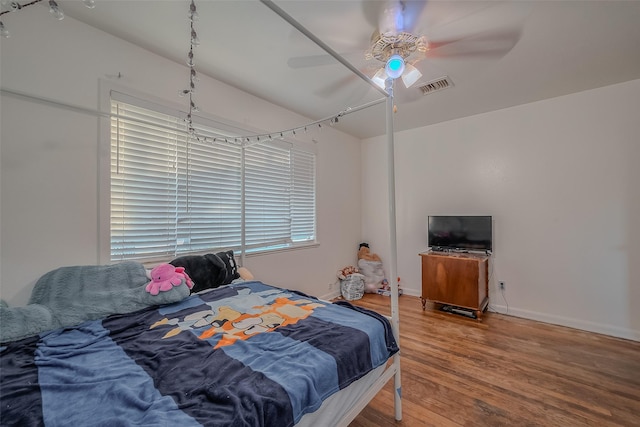 bedroom with ceiling fan, baseboards, wood finished floors, and visible vents