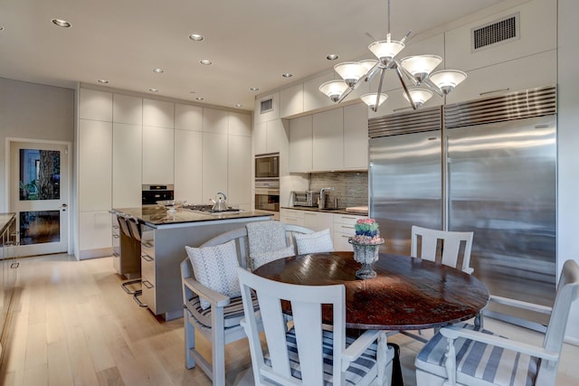 2003 Arrowwood Cir N, Houston, TX 77063 - kitchen featuring light wood finished floors, a kitchen island with sink, modern cabinets, built in appliances, and visible vents