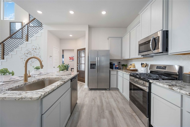 16833 Needlepoint Dr, Conroe, TX 77302 - kitchen with recessed lighting, stainless steel appliances, a sink, light wood-type flooring, and light stone countertops