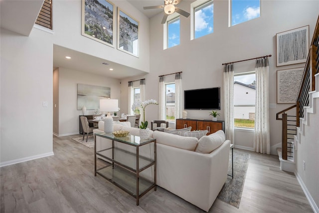 16833 Needlepoint Dr, Conroe, TX 77302 - living area featuring a towering ceiling, baseboards, a ceiling fan, wood finished floors, and stairway