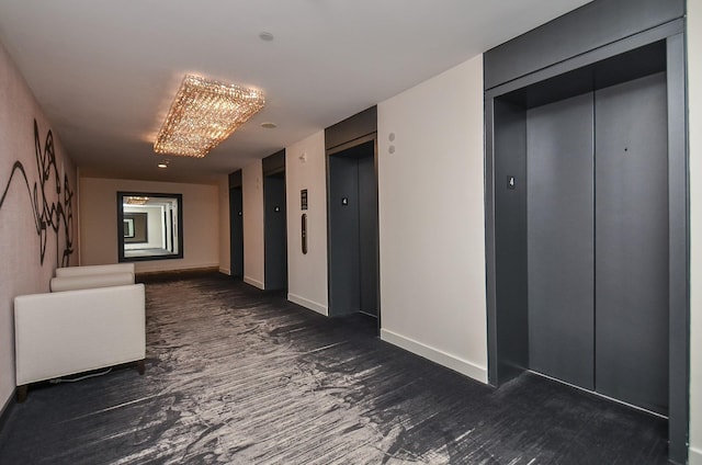 hallway featuring baseboards, wood finished floors, and elevator