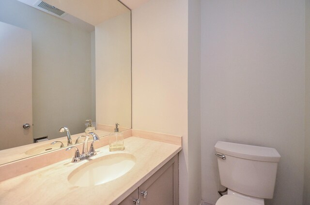 half bath with visible vents, vanity, and toilet