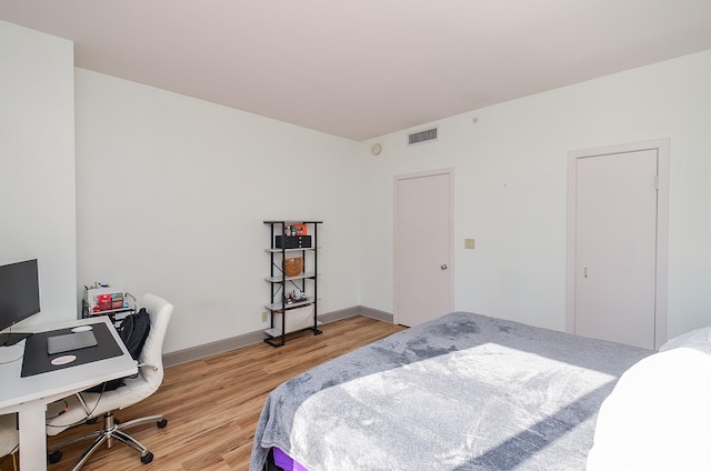 bedroom with baseboards, visible vents, and light wood-type flooring