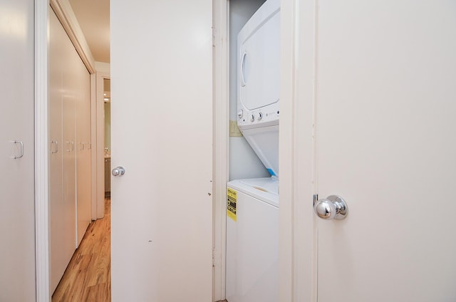 laundry room featuring stacked washer and clothes dryer and light wood finished floors