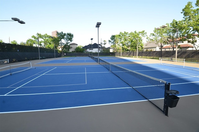 view of tennis court with community basketball court and fence
