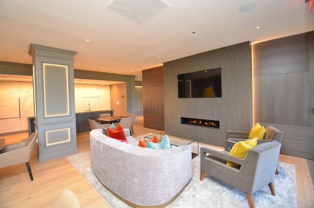 living area with light wood-style flooring, a large fireplace, and recessed lighting