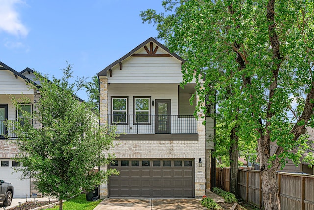 view of front facade featuring a balcony, concrete driveway, stone siding, fence, and a garage
