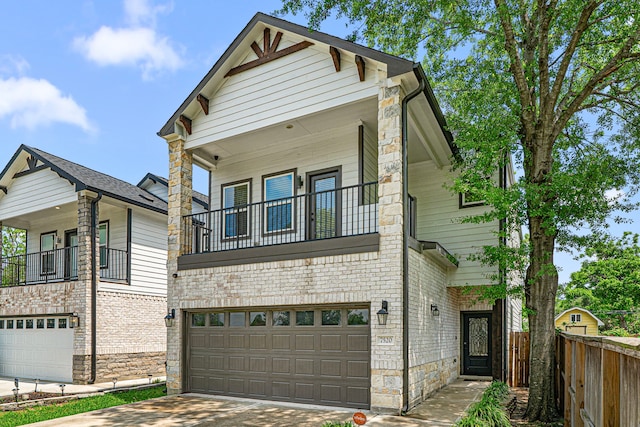 view of front of house featuring driveway, fence, brick siding, an attached garage, and a balcony