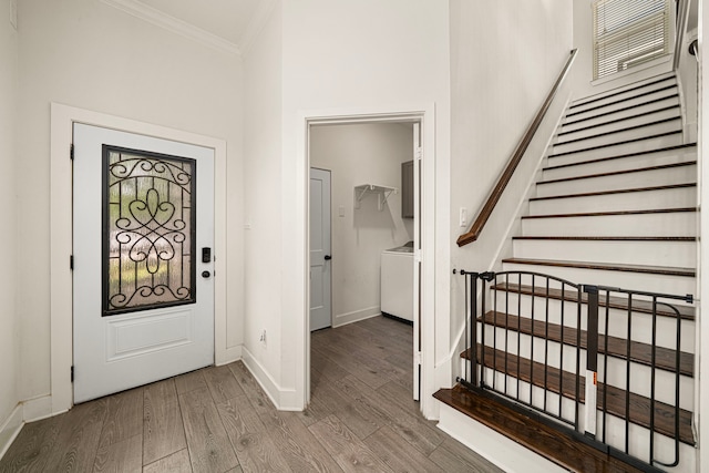 foyer featuring stairway, wood finished floors, crown molding, baseboards, and washer / clothes dryer