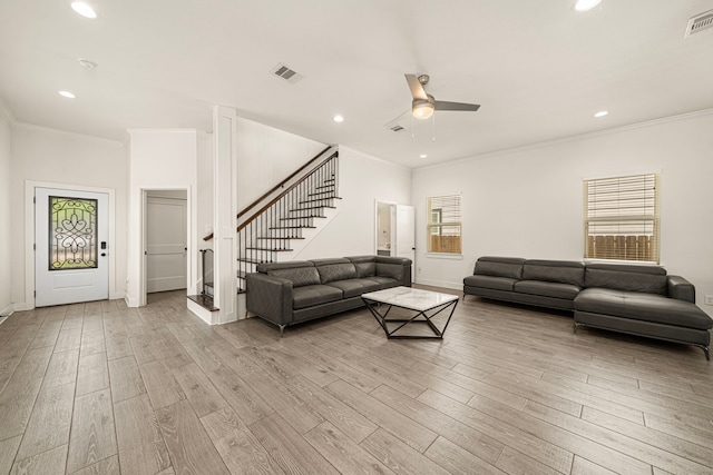 living area with plenty of natural light, visible vents, stairs, and ceiling fan