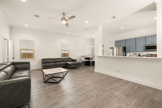 living area featuring wood finished floors, visible vents, a ceiling fan, and ornamental molding