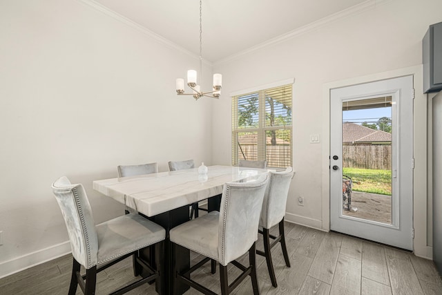 dining space featuring baseboards, an inviting chandelier, ornamental molding, and light wood-style flooring