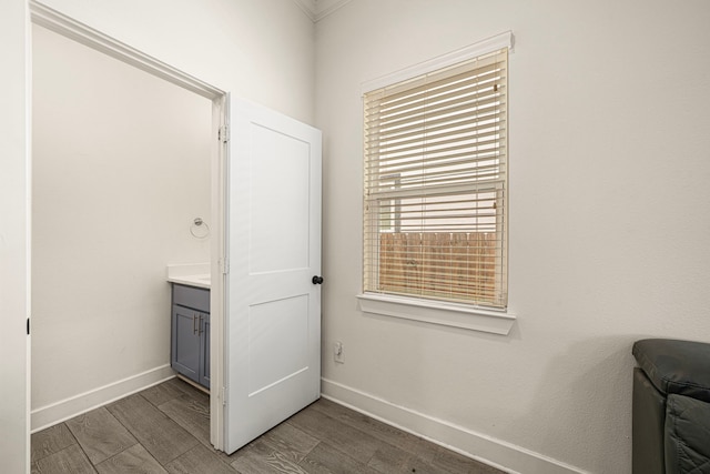 interior space featuring wood finished floors, baseboards, and ornamental molding