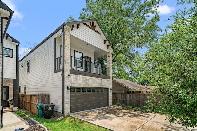 view of front of property with a balcony, concrete driveway, fence, a garage, and brick siding