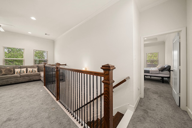 hallway featuring ornamental molding, a healthy amount of sunlight, an upstairs landing, and carpet