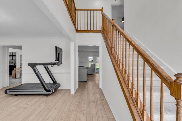 interior space featuring crown molding, ceiling fan, wood finished floors, and a towering ceiling