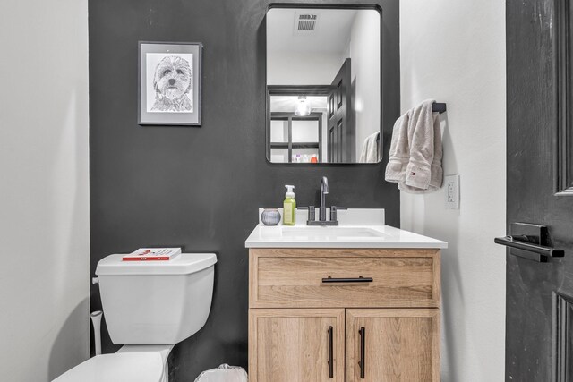 half bathroom with vanity, toilet, and visible vents
