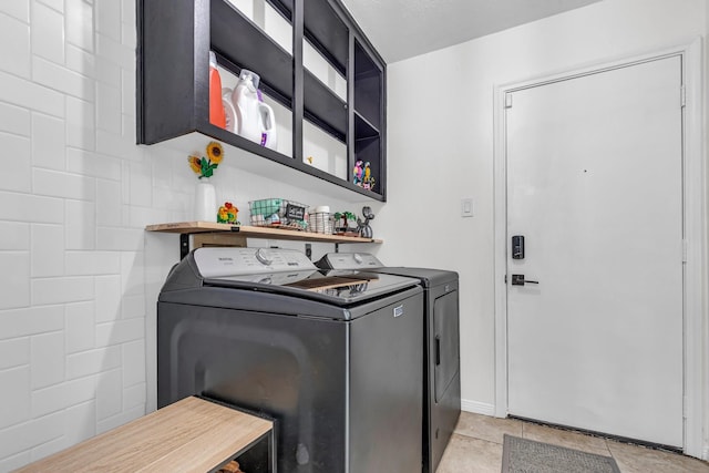clothes washing area with laundry area, washing machine and dryer, and light tile patterned flooring