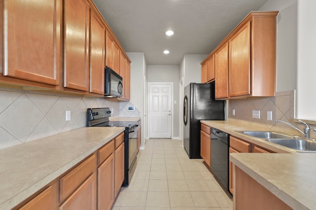 kitchen featuring recessed lighting, light countertops, a sink, light tile patterned flooring, and black appliances
