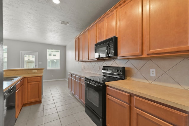 kitchen featuring tasteful backsplash, black appliances, light tile patterned flooring, light countertops, and baseboards