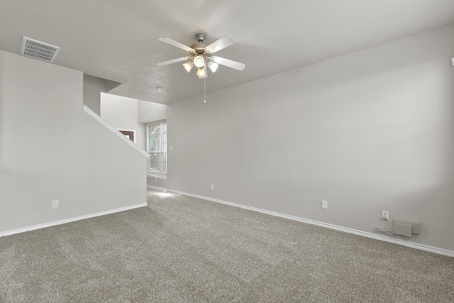 carpeted spare room with stairway, baseboards, a ceiling fan, and visible vents