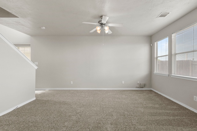 carpeted spare room featuring baseboards, a ceiling fan, and visible vents