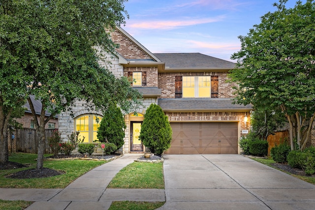 traditional-style home with brick siding, an attached garage, fence, and driveway