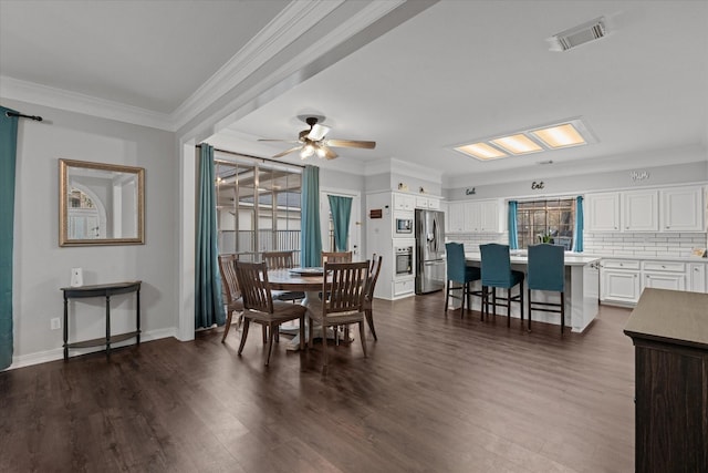 dining room with ornamental molding, visible vents, dark wood finished floors, ceiling fan, and baseboards