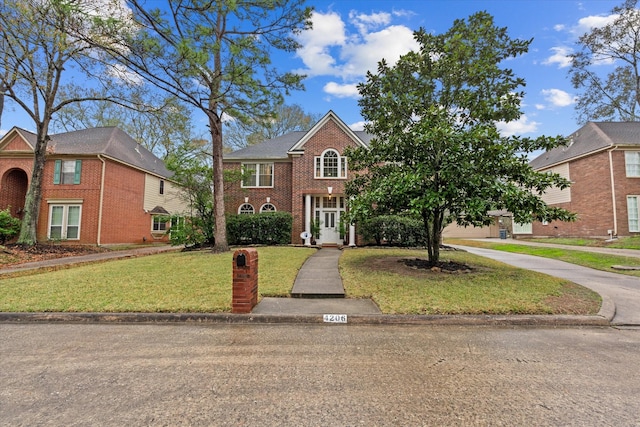 view of front of house with a front lawn, brick siding, and driveway
