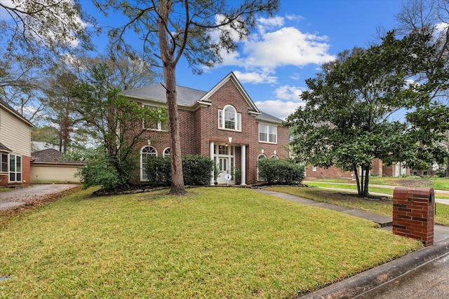 georgian-style home featuring a front lawn and brick siding