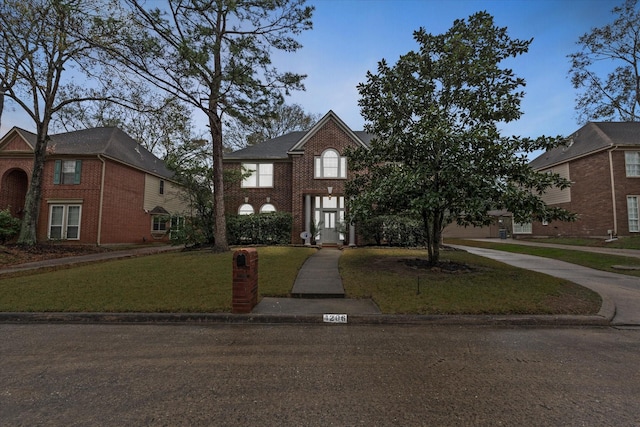 view of front of house featuring a front lawn, concrete driveway, and brick siding