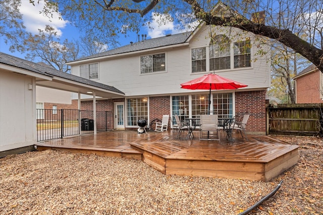 rear view of house with fence, outdoor dining space, brick siding, and a deck