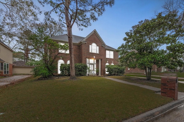 view of front facade with brick siding and a front yard