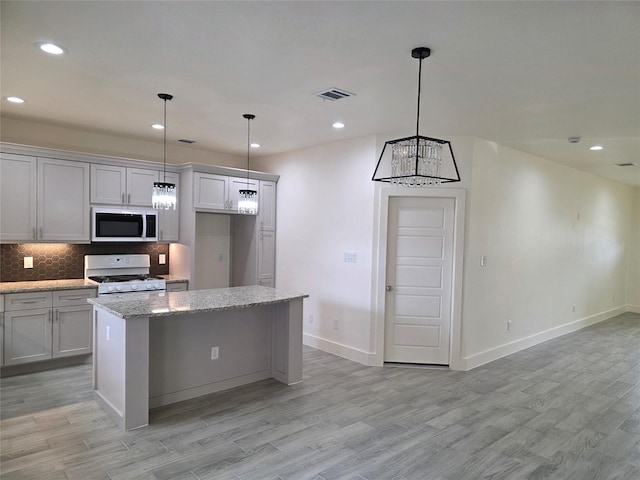 2140 De Soto St, Houston, TX 77091 - kitchen featuring decorative backsplash, visible vents, a center island, gas range gas stove, and light wood finished floors